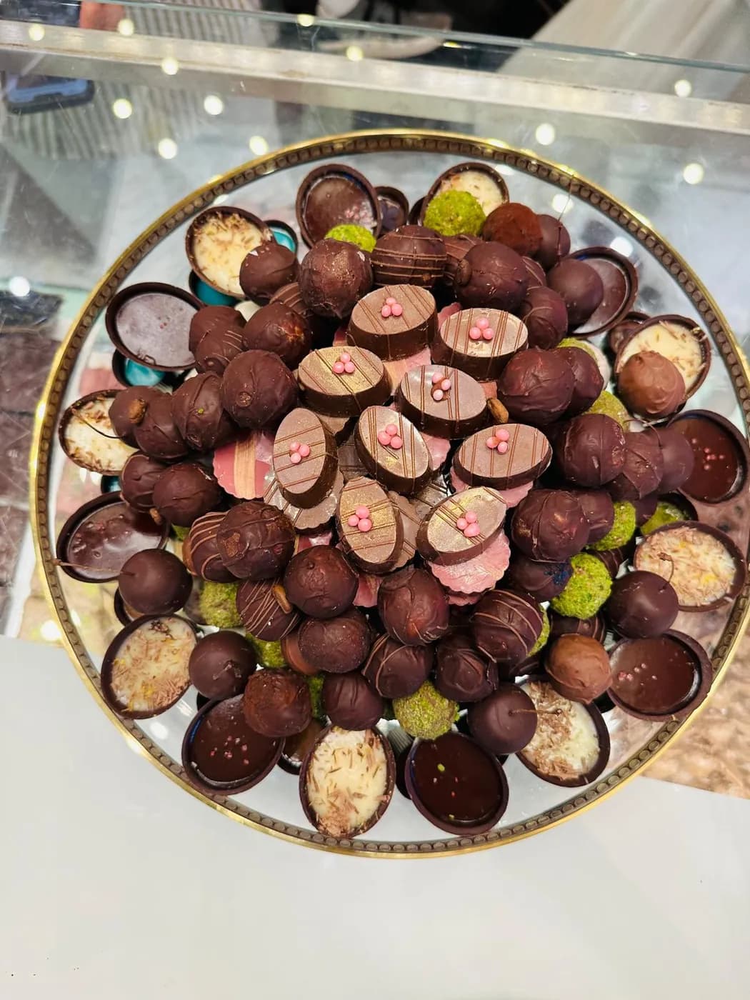 Cam tepside pembe şeker süslemeli oval çikolatalar ve truffle çeşitleri